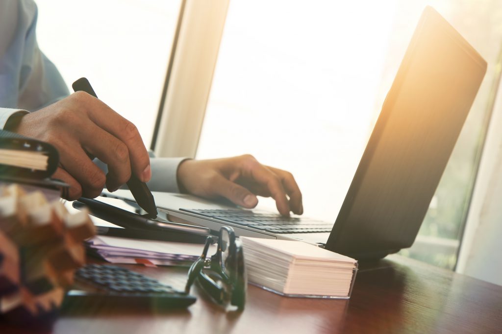 Businessman hand using laptop and mobile phone with overcast eff