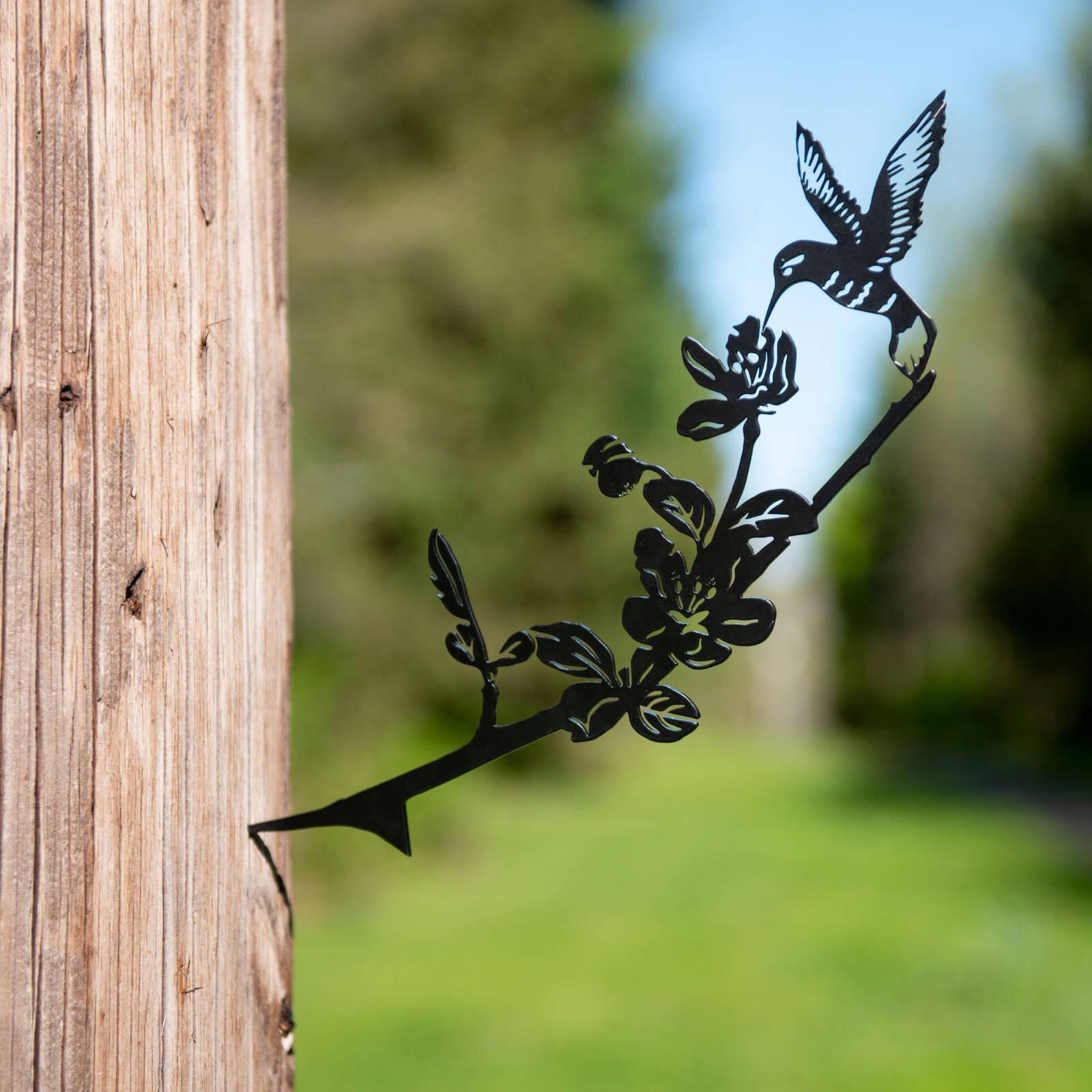 Metal hummingbird on wood pole yard decor product photography image