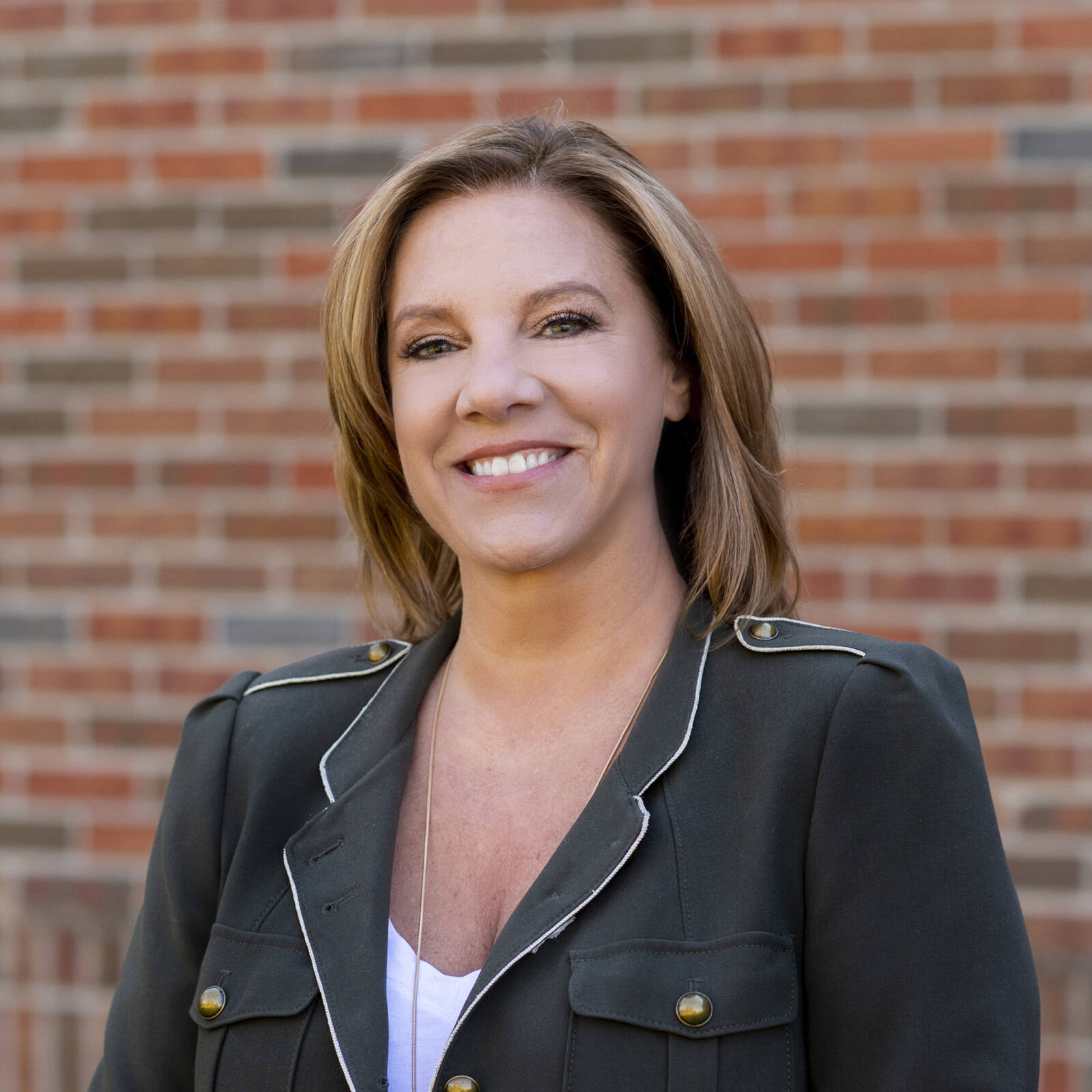 smiling business woman headshot with brick wall backdrop